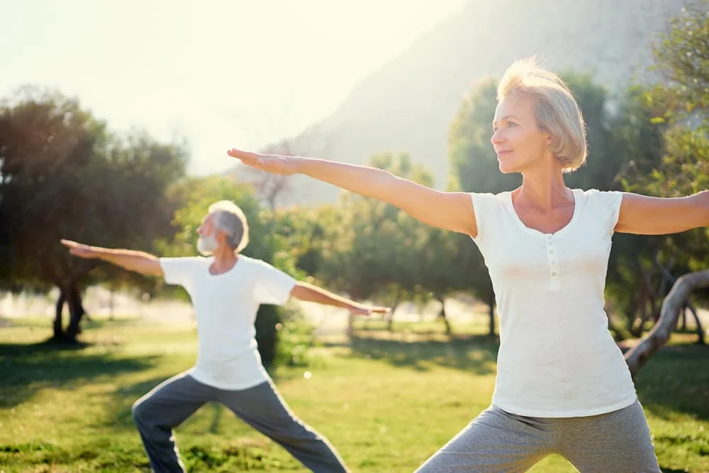 Yoga at park. Senior family couple exercising outdoors. Concept of healthy lifestyle